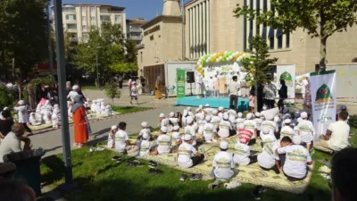 Etkinlikte çocuklar pankartlarla yürürken program tilavet, şiir, ilahi ve gösterilerle