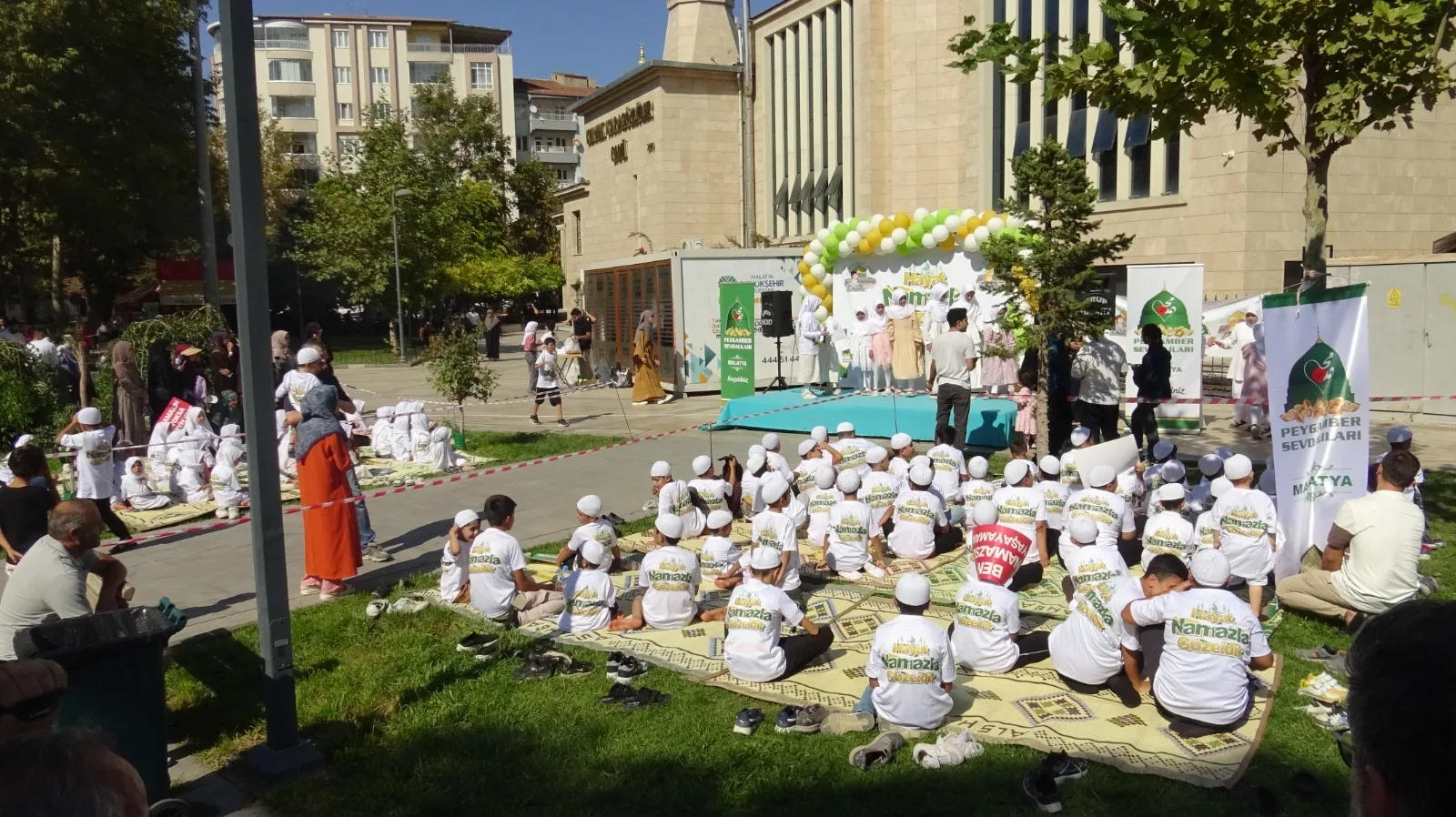Etkinlikte çocuklar pankartlarla yürürken program tilavet, şiir, ilahi ve gösterilerle